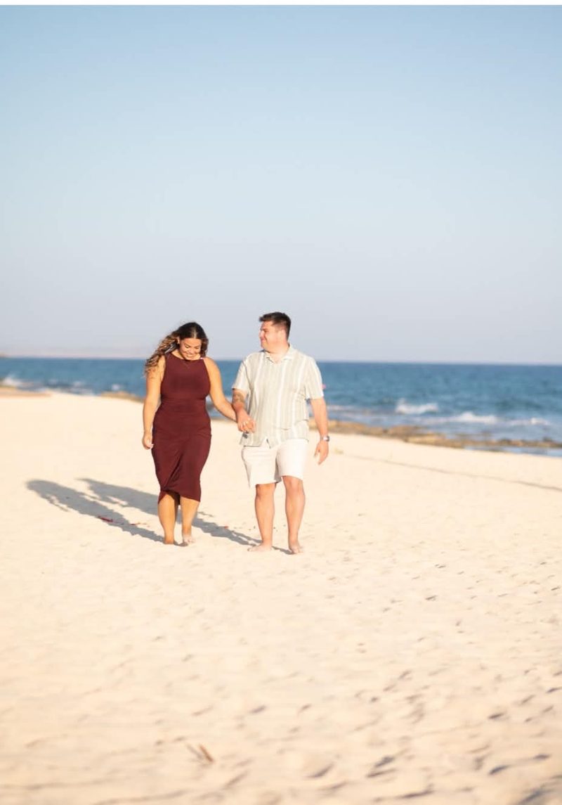 Liam and Andrea walking hand in hand on the sand